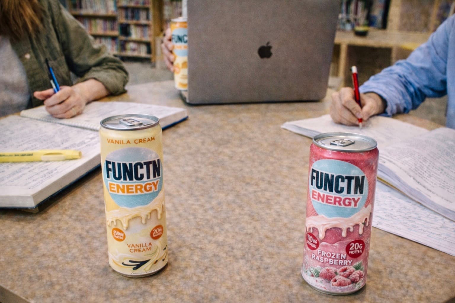 Two FUNCTN Energy cans on a study table with students